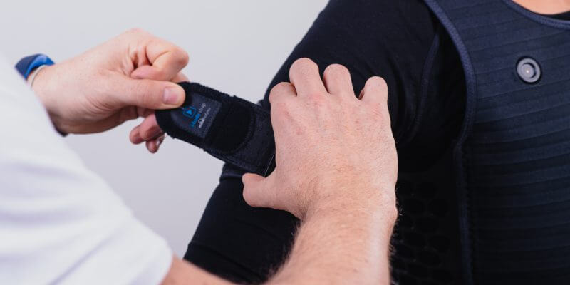 Nahaufnahme beim Anlegen einer Armmanschette durch einen Trainer
