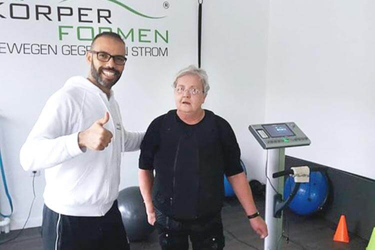 Trainer mit einer Kundin am EMS Gerät