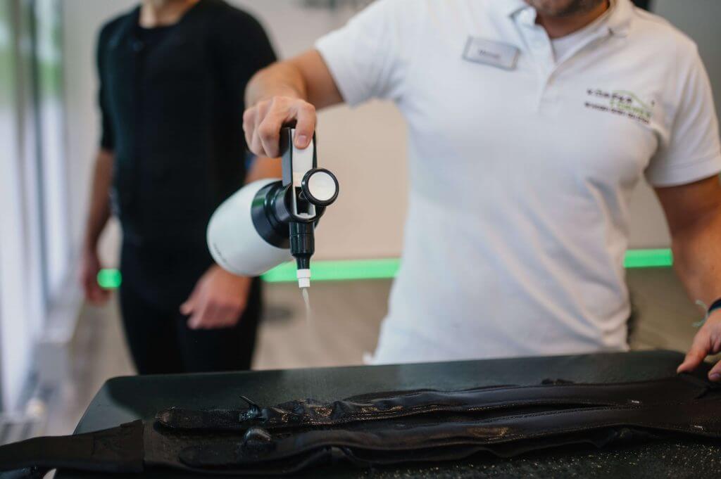 Trainer der eine Armmanschette einsprüht