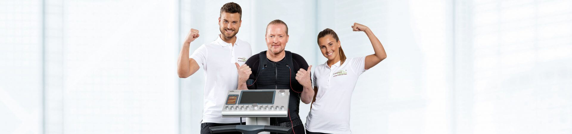 Joey Kelle zwischen zwei Trainern an einem EMS Gerät