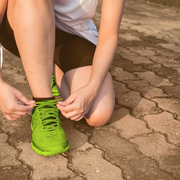 Eine knieende Läuferin die sich den Schuh zu bindet